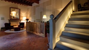 A staircase with a wooden handrail and a stone wall with a fireplace.