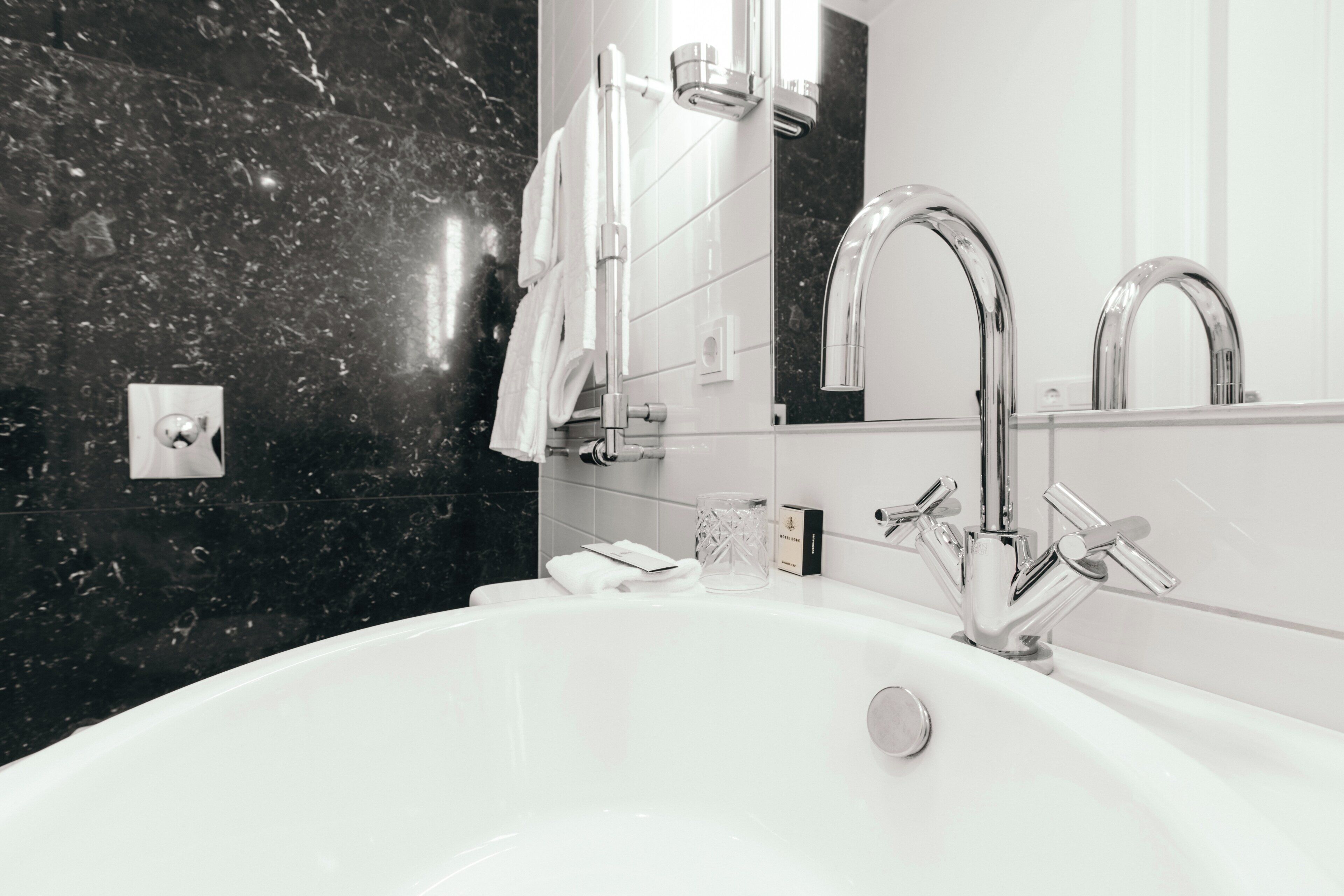 A modern bathroom with a white bathtub, chrome fixtures, and a marble backsplash.