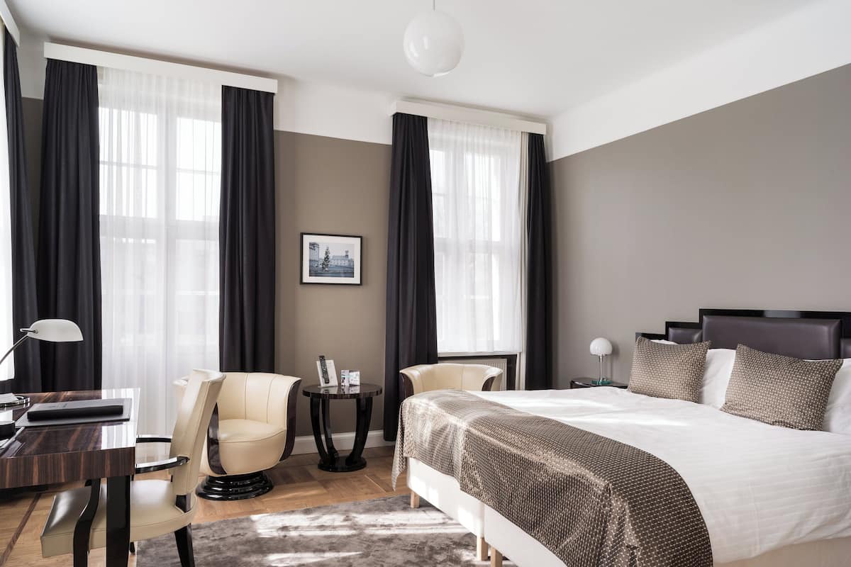 Een moderne hotelkamer met een groot bed, twee stoelen, een tafeltje en een bureau.