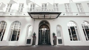 Valkoinen rakennus, jossa on suuri sisäänkäynti, kaarevat ikkunat ja kyltti, jossa lukee ”HOTEL BORG”.