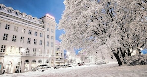 Un edificio imbiancato dalla neve, con molte finestre e un albero sullo sfondo.