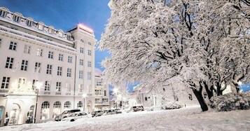 Un edificio cubierto de nieve con numerosas ventanas y un árbol en primer plano.