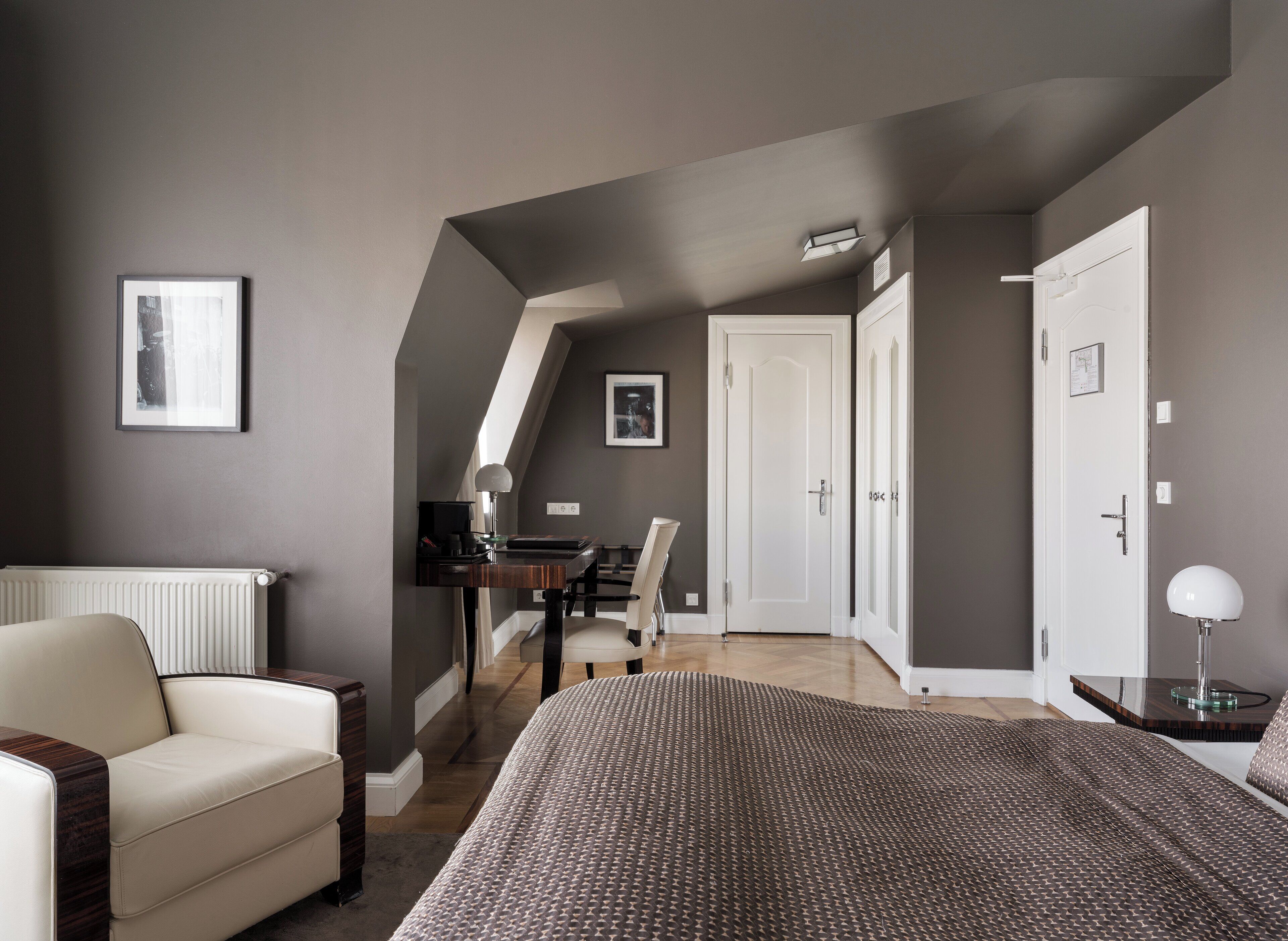 A bedroom with a bed, a desk, a chair, and a radiator.