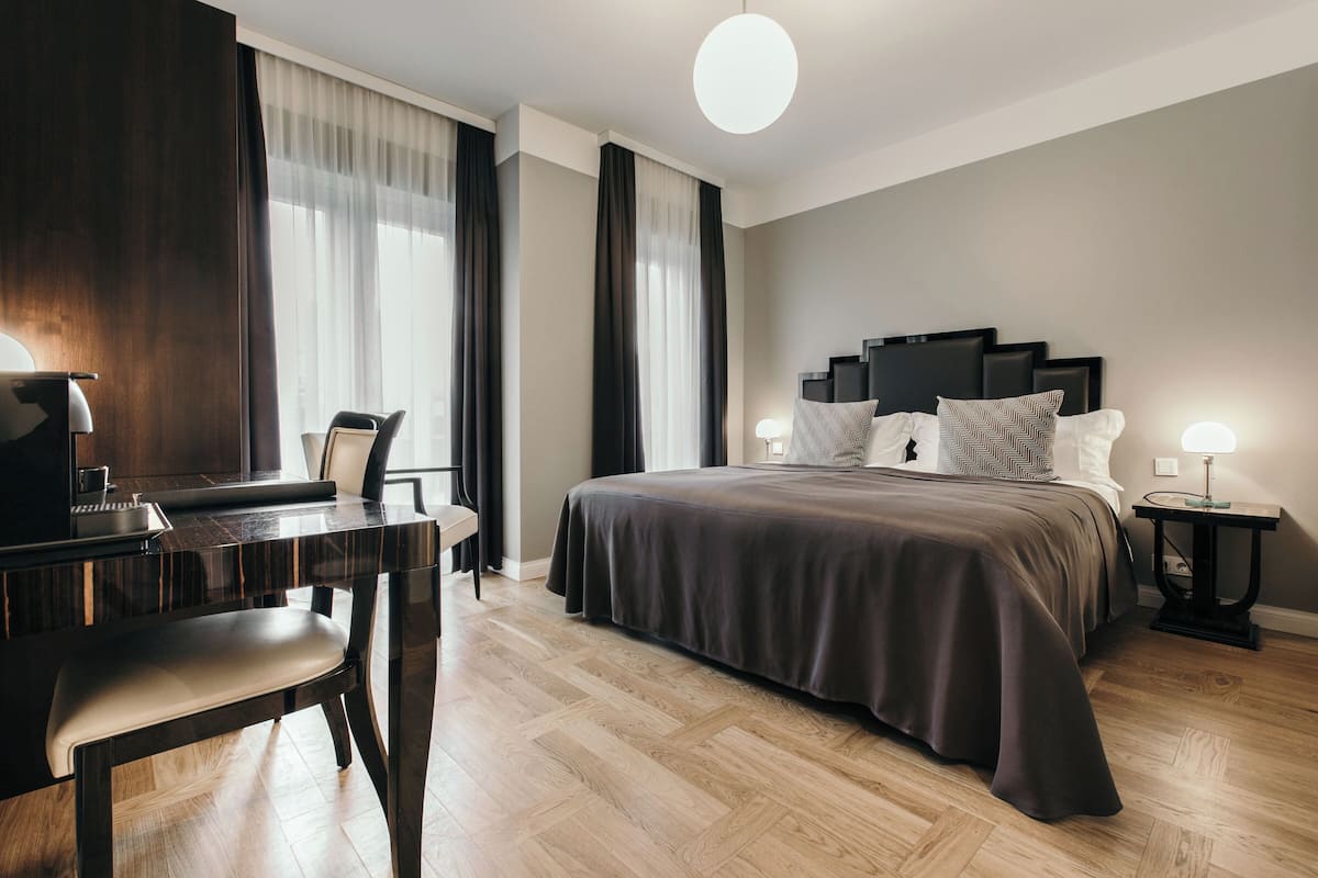 Een moderne hotelkamer met een groot bed, een bureau met een stoel, en een piano.