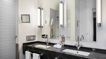 A modern bathroom with two sinks, a large mirror, and a towel rack.