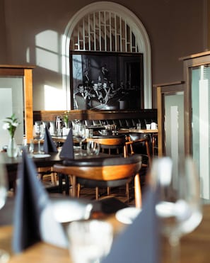 A restaurant interior with a bar area, tables set for dining, and a framed picture on the wall. - Hotel Borg by Keahotels (Reykjavik)