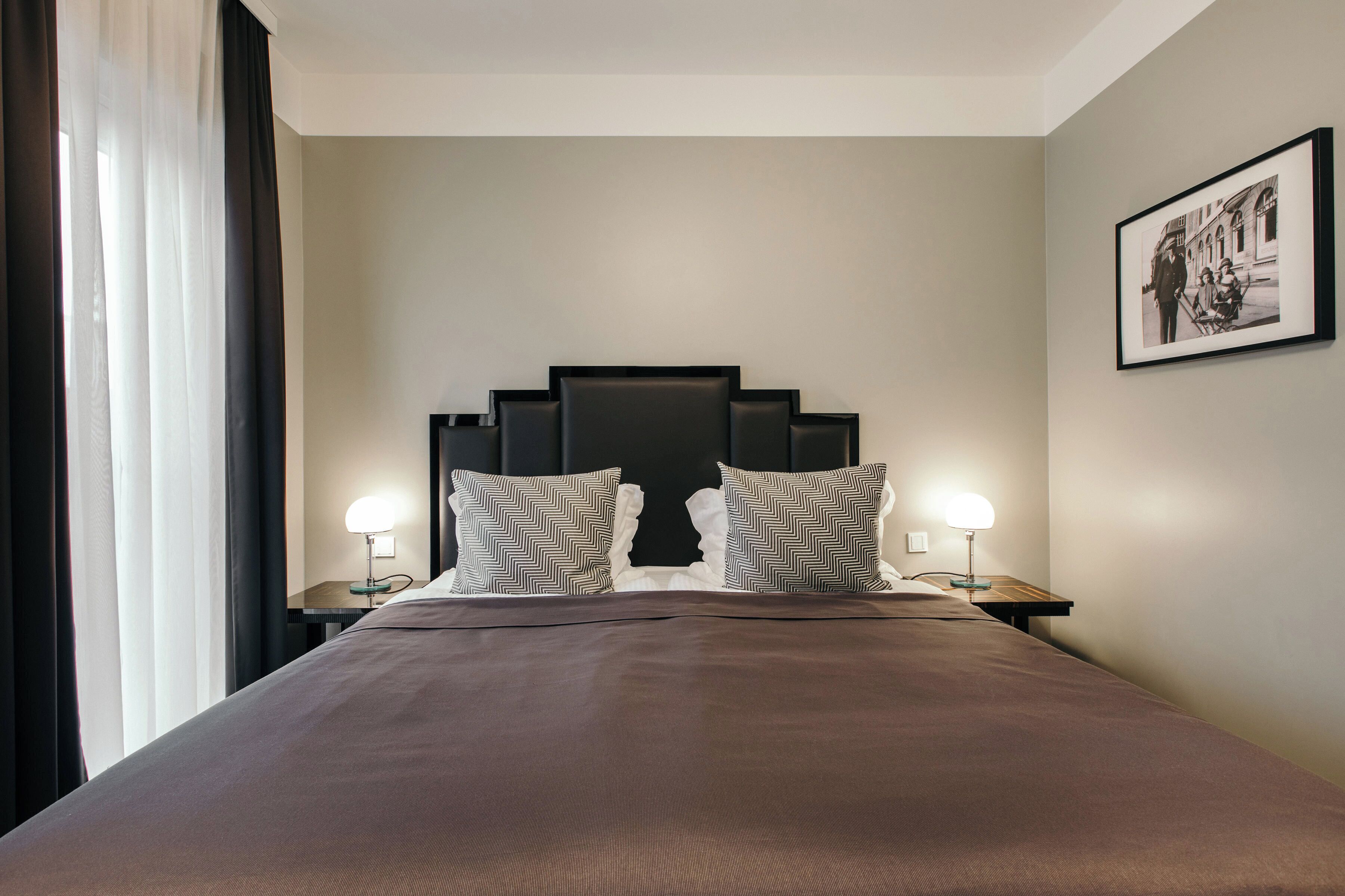 A hotel room with a large bed, two nightstands, a headboard, and a framed picture on the wall.
