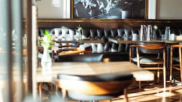 A restaurant interior with a long dining table, cushioned seating, and a large framed photograph on the wall.