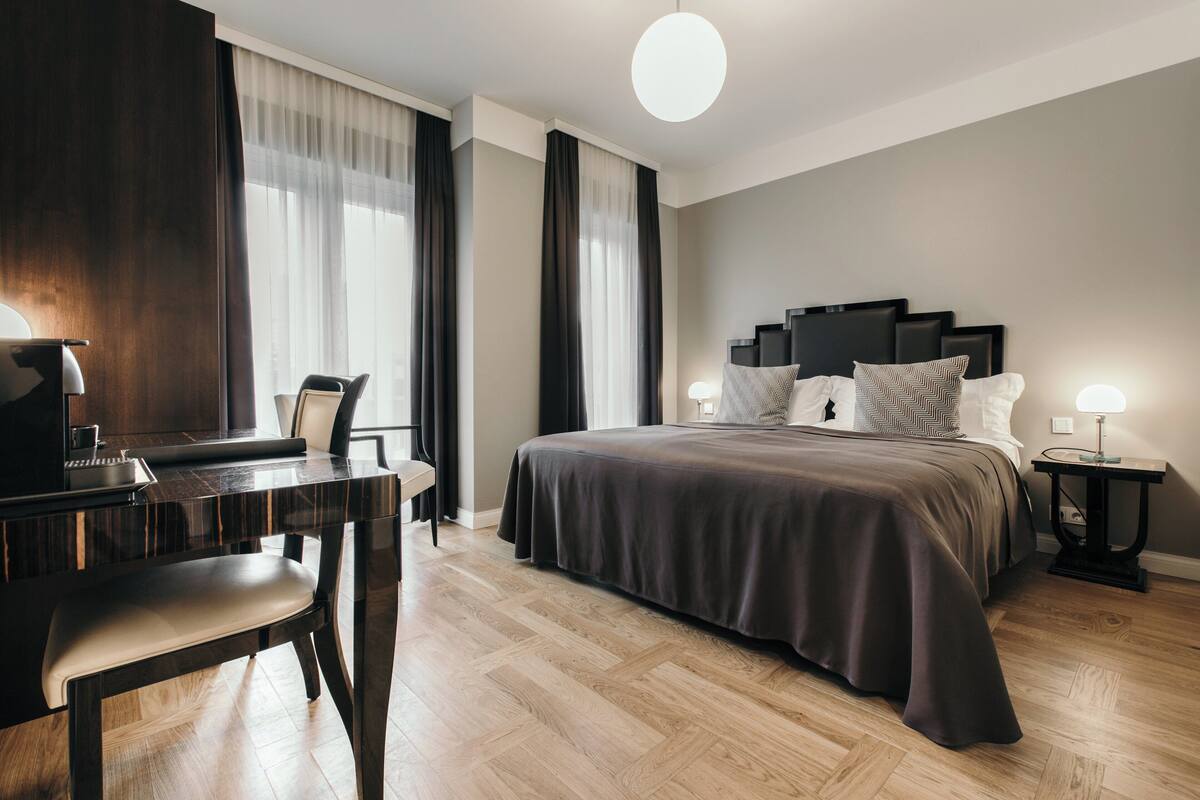Een moderne hotelkamer met een groot bed, een bureau met een piano en uitzicht op de stad.