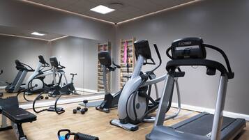 A gym with various exercise equipment including treadmills, an elliptical, and free weights.