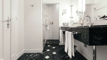 Un baño moderno con suelo de mármol negro, paredes blancas y encimera negra.