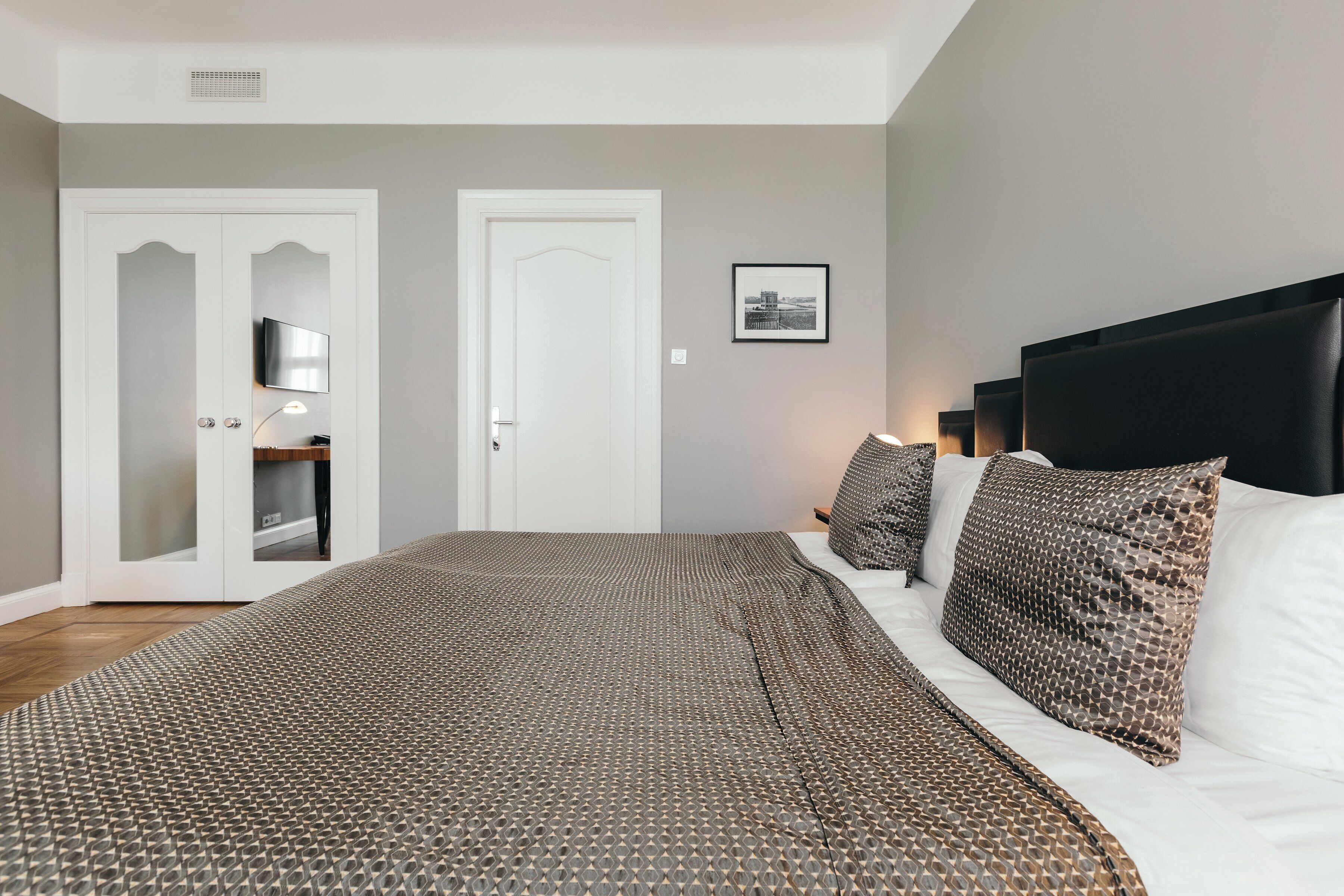 Une chambre à coucher avec un grand lit, une armoire avec un miroir et un tableau encadré au mur.