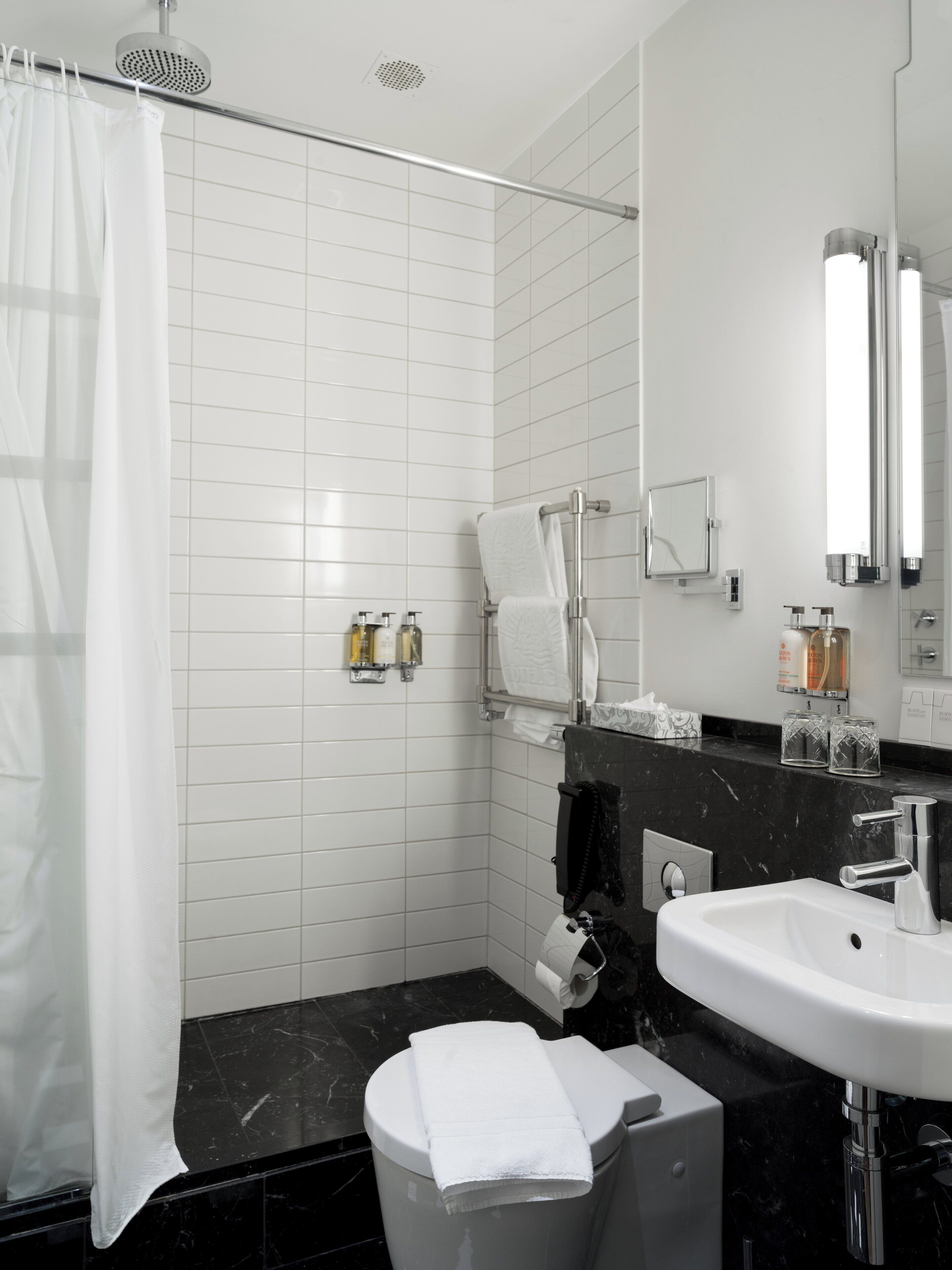 A modern bathroom with a shower, toilet, sink, and a large mirror.