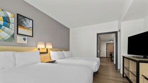 Una habitación de hotel con dos camas, un televisor y obras de arte en la pared.