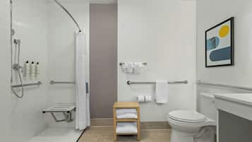 A modern bathroom with a shower, toilet, and a small wooden shelf with towels.