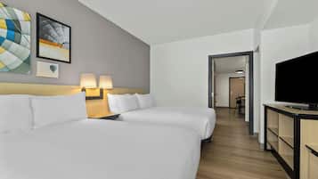 A hotel room with two beds, a TV, and artwork on the wall.