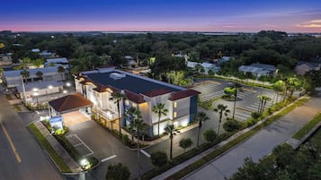 A multi-story building with a parking lot, surrounded by trees and a clear sky.