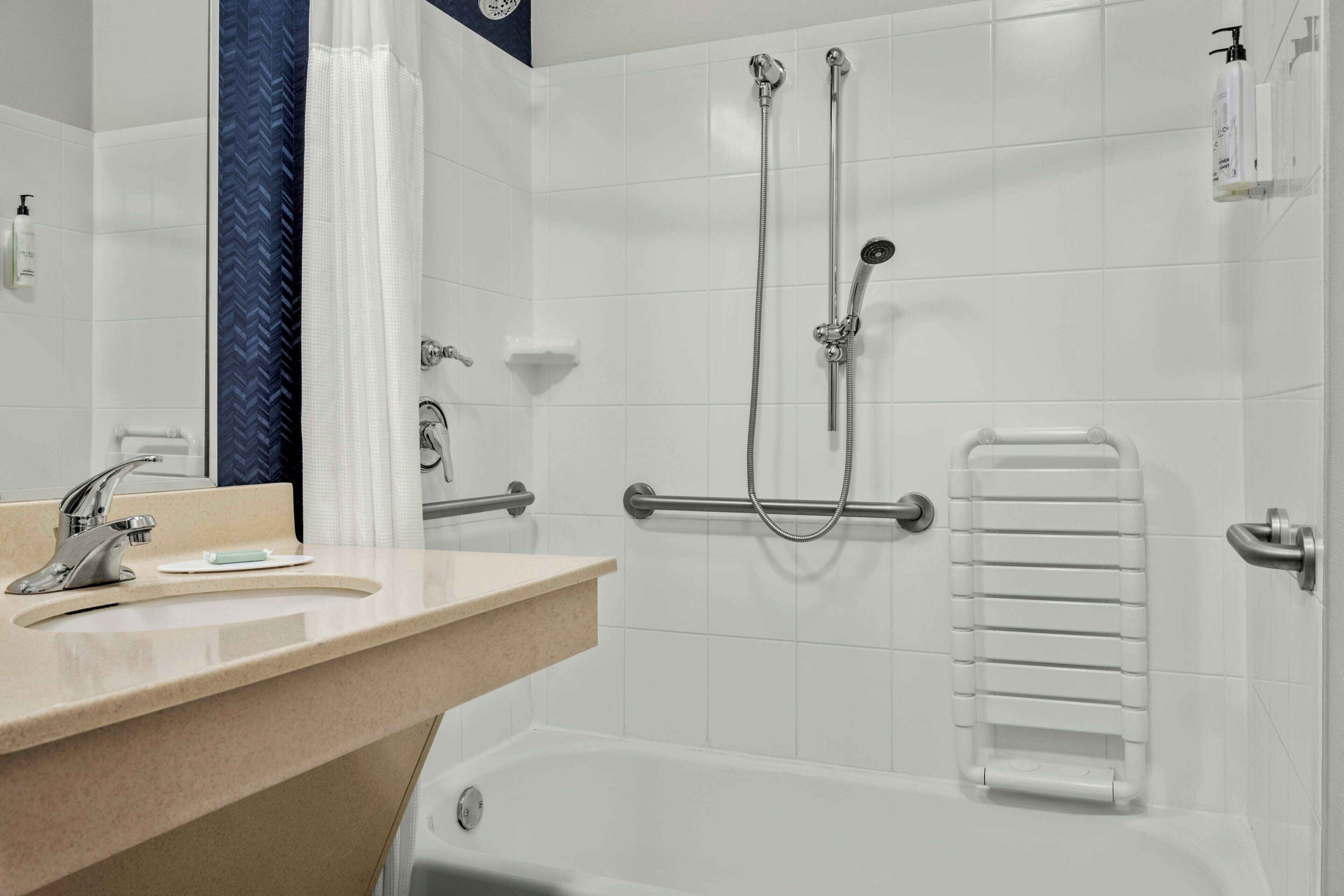 Een moderne badkamer met een wastafel, spiegel, douche en een handdoekhouder.