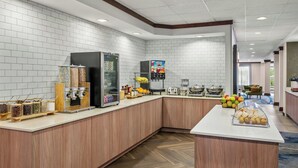 A modern kitchen area with a central island, a refrigerator, a coffee machine, and a fruit display. - Fairfield Inn and Suites by Marriott Marion (Marion)