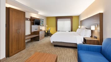A hotel room with a bed, a desk with a chair, a television, and a sofa.