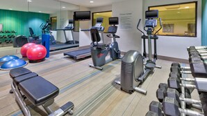 Ein Fitnessstudio mit Laufbändern, Crosstrainern und Kurzhanteln.
