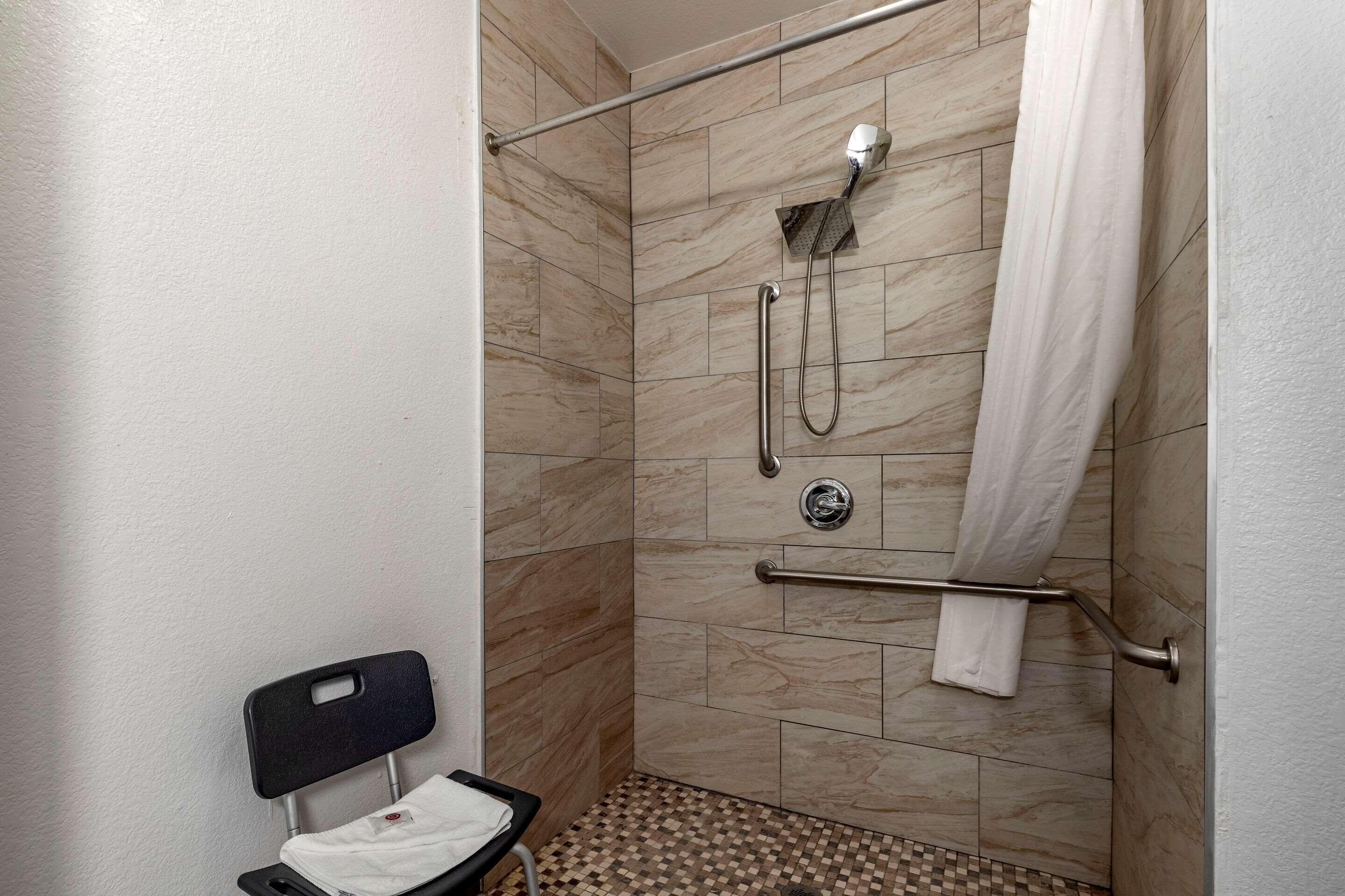 A shower with a handheld showerhead, a towel rack, and a grab bar.