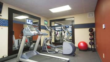 A gym with treadmills, elliptical machines, and exercise balls.