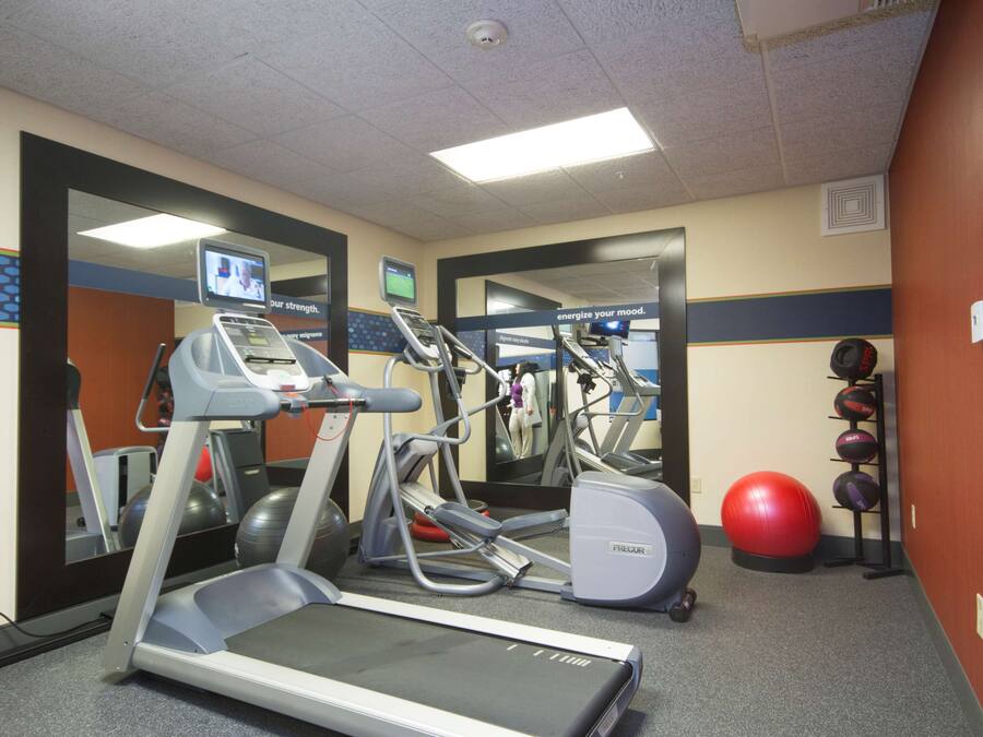 A gym with treadmills, elliptical machines, and exercise balls.