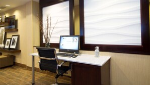 Ein Hotelrezeptionstresen mit einem Laptop, einem Stuhl und einer Vase mit Zweigen.