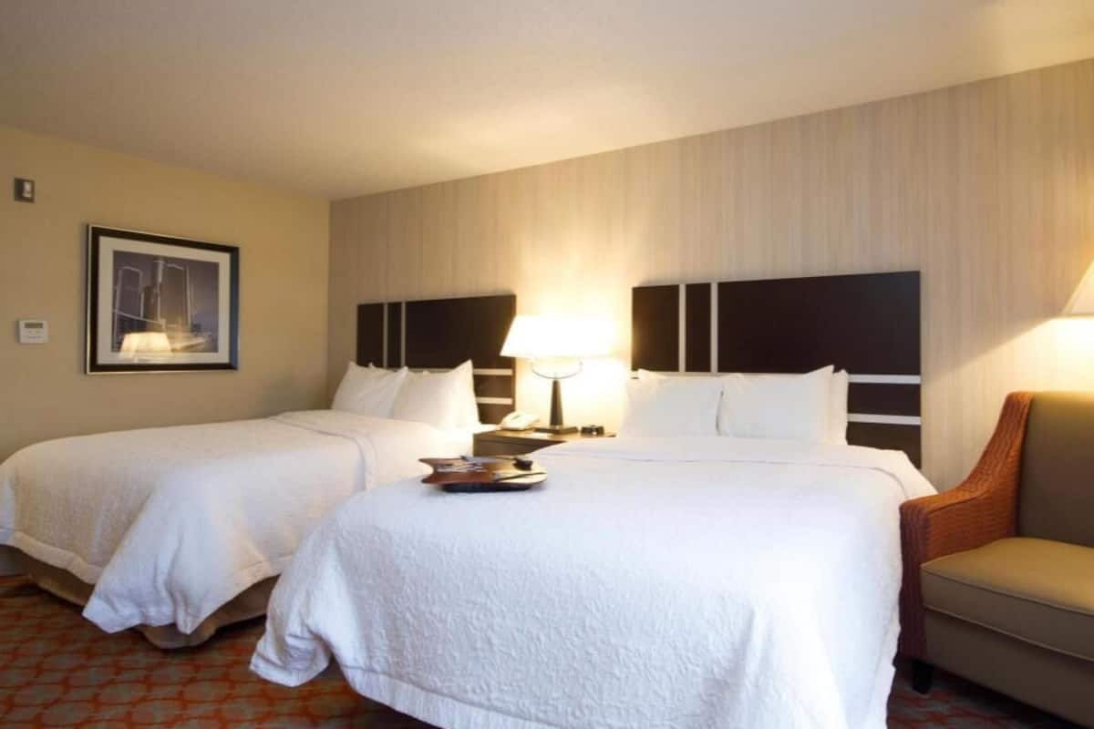 Une chambre d’hôtel avec deux lits, un canapé, une lampe et un tableau encadré au mur.