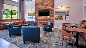 A modern hotel lobby with a large TV, comfortable seating, and a view of the outdoors. - Hampton Inn & Suites Spartanburg-I-26-Westgate Mall (Spartanburg)