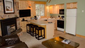 A cozy living room with a fireplace, a TV mounted on the wall, and a coffee table. - Mount Bachelor Village Resort (Bend)