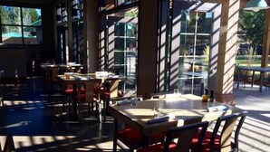 An indoor dining area with tables and chairs, large windows, and a view of the outdoors. - Mount Bachelor Village Resort (Bend)