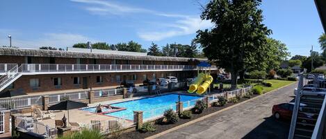A motel with a pool, outdoor seating, and a yellow slide.
