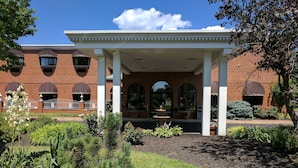 A building with a covered entrance, brick walls, and arched windows. - South Shore Inn (Sandusky)