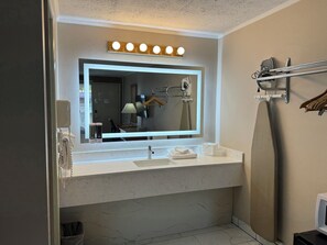Un baño con un espejo grande, tocador y zona de ducha.