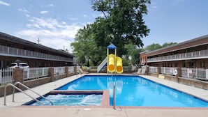 A swimming pool with a slide, surrounded by a fence, and adjacent to a building with a balcony. - South Shore Inn (Sandusky)
