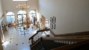 A spacious interior with a grand chandelier, arched windows, and a wooden staircase. - South Shore Inn (Sandusky)