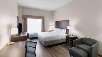 Een hotelkamer met een bed, een bureau, een stoel, een televisie en een raam met gordijnen.