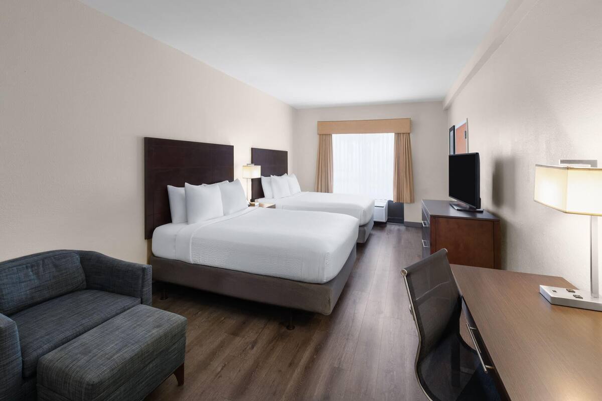 Une chambre d’hôtel avec deux lits, un canapé, un bureau et une télévision.