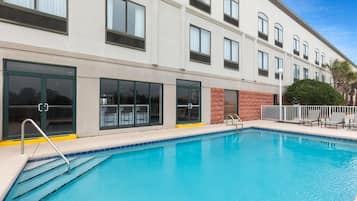 A modern hotel with a swimming pool, large windows, and a brick facade.