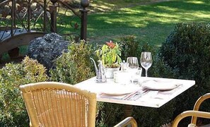An outdoor dining table set with chairs, a potted plant, and wine glasses. - Mas de la Senancole & Spa (Gordes)