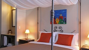 Une chambre d’hôtel avec un lit à baldaquin, un tableau au mur et une salle de bain équipée d’un porte-serviettes.