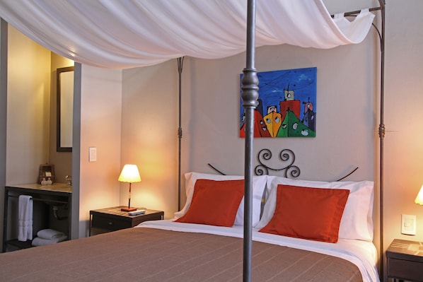 Une chambre d’hôtel avec un lit à baldaquin, un tableau au mur et une salle de bain équipée d’un porte-serviettes.