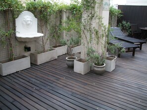 Un rivestimento in legno con fioriere e un muro in pietra con una scultura di testa di leone.
