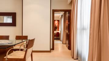 A hotel room with a dining area, a mirror, and a view of a hallway with a door.