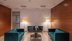 Un hall d’entrée moderne avec deux canapés de couleur turquoise, une table basse centrale et deux lampadaires.