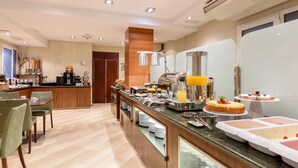 Un espace dédié au petit-déjeuner à l’hôtel, avec un buffet proposant notamment un coin café, des fruits et un présentoir de gâteaux.