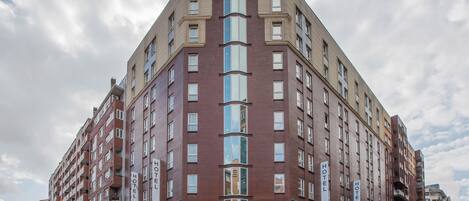 A multi-story hotel with a corner entrance, large windows, and a brick facade.