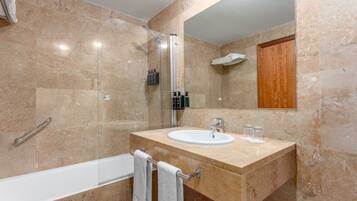 Un baño moderno con cabina de ducha de vidrio, un lavabo blanco y un mueble de madera.